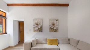 Un salon moderne avec un canapé beige, une table basse en bois et deux tableaux aux motifs floraux accrochés au mur.