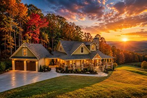 A large, multi-story house with a stone chimney, a covered porch, and a driveway leading to a garage. - Epic Views • Hot Tub • Game Room • Sleeps 12 - Holiday Home (Morganton)