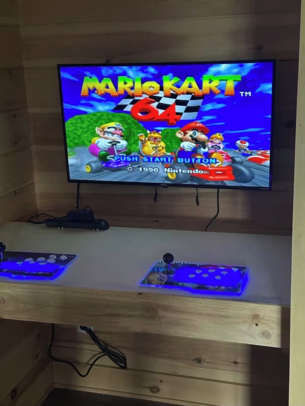 A television displaying a Mario Kart game, a wooden desk, and a DJ controller.