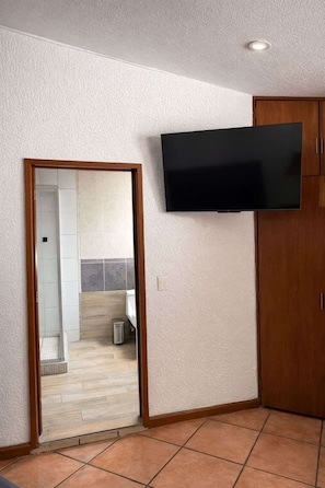 A room with a flat-screen TV mounted on the wall, a wooden wardrobe, and a tiled floor. - Suite Privada Double, Zona Consulado (Zapopan)