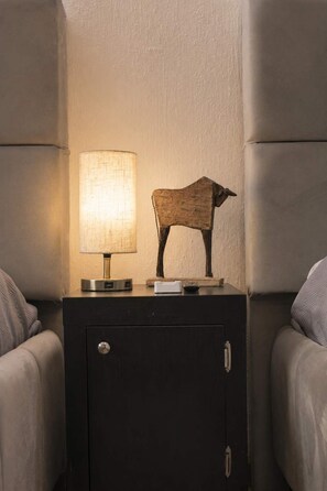 Ein Nachttisch mit Lampe und einer Skulptur einer Holz-Kuh.