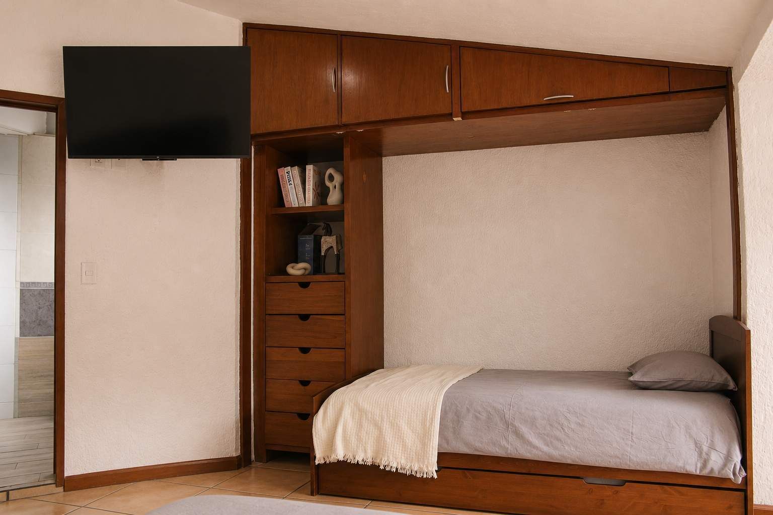Un dormitorio con cama, armario y televisor.