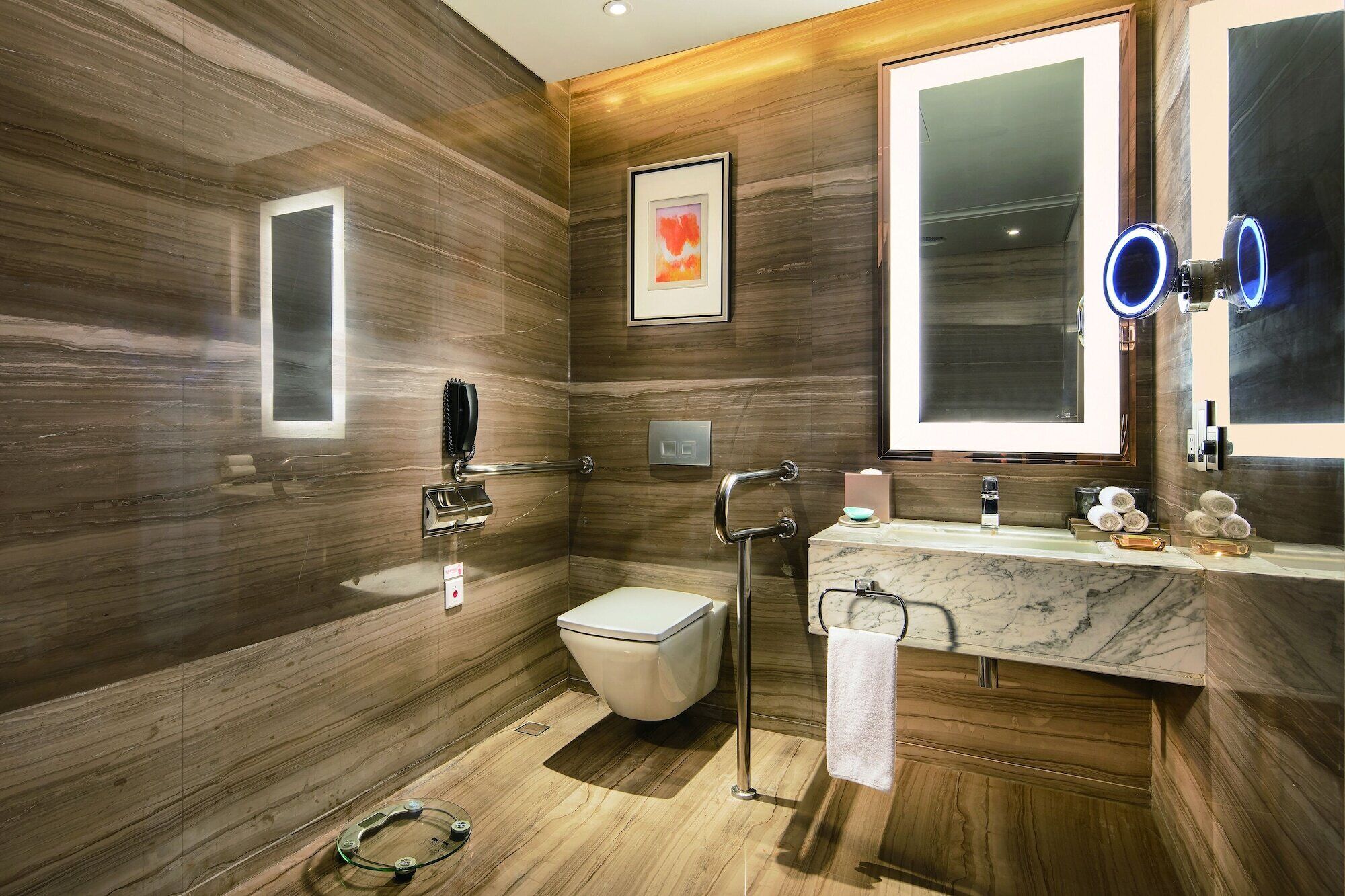 A modern bathroom with a wooden wall design, a toilet, a sink with a marble countertop, and a large mirror with a blue light.