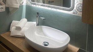 Un baño con lavamanos blanco, espejo con luces LED y baldosas decorativas en las paredes.