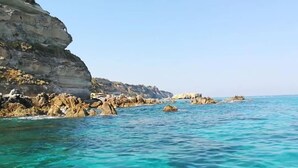 Un paisaje costero con agua turquesa cristalina, formaciones rocosas y un acantilado.