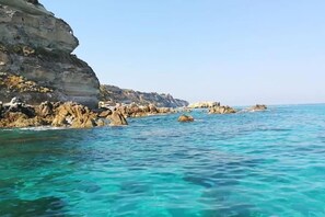Eine Küstenlandschaft mit klarem türkisblauem Wasser, Felsformationen und einer Klippe.