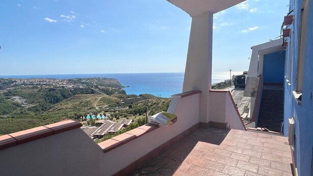 Un balcón con vista al mar y un pueblo distante.