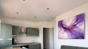Un espacio habitable moderno con comedor, cocina y un gran cuadro abstracto en la pared.