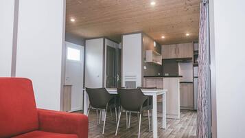 A compact living space with a dining area, kitchenette, and a red sofa.