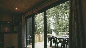 A room with a wooden ceiling, a sliding glass door leading to an outdoor deck with a table and chairs. - Villa (Malansac)
