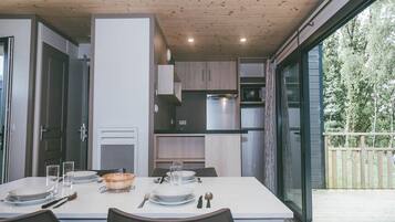 A modern kitchen with built-in appliances, a dining table set for four, and a view of the outdoors.
