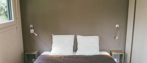 Un dormitorio con una cama, dos mesitas de noche y un ventanal.