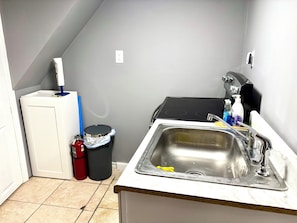 A kitchen with a sink, stove, and a small trash bin.