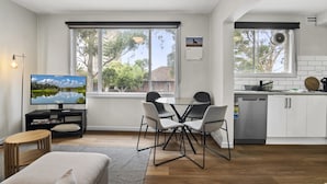 Un salon moderne comprenant un téléviseur, une table à manger, des chaises et un canapé.