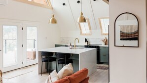 Une cuisine moderne dotée d’un îlot central, de luminaires suspendus et d’un coin repas avec des chaises.