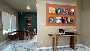 A room with a dining table, benches, a wall with framed pictures, and a small table with a sign. - Gem On Pearl w/ Pool - Walk to Downtown Lockhart (Lockhart)