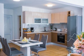 Una cocina moderna con comedor, que incluye horno empotrado, cafetera y refrigerador.