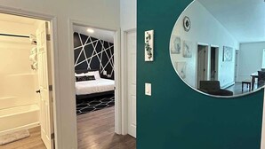 Ein modernes Interieur mit einer türkisblauen Akzentwand, einem runden Spiegel und einem Bett mit einem geometrischen Kopfstück.