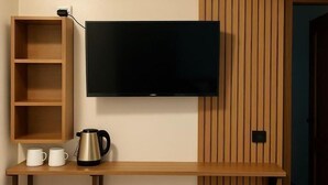 Ein modernes Wohnzimmer mit einem an der Wand montierten Flachbildfernseher, Holzregalen, einem Couchtisch und einer Tür mit vertikalen Holzleisten.