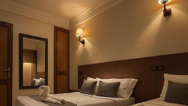 Ein Hotelzimmer mit zwei Betten, einem großen Spiegel und Wandleuchten.
