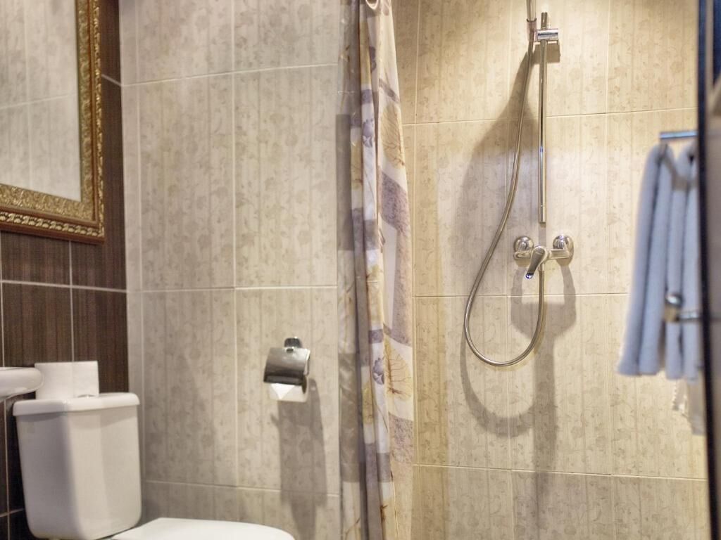 A bathroom with a toilet, a shower with a curtain, and a towel rack.