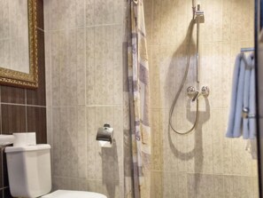 A bathroom with a toilet, a shower with a curtain, and a towel rack. - Isni appart hotel (Agadir)