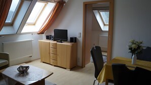 A room with a desk, a chair, a cabinet with a flat-screen TV, a radiator, and skylights. - Wittow Apartment for 2 Guests (50 m²) in Wiek on Rügen (Wiek)