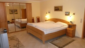 Quarto com cama de madeira, mesas de cabeceira, espelho e televisão.
