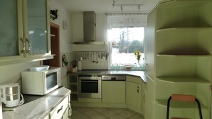 Cozinha equipada com micro-ondas, forno e diversos utensílios.