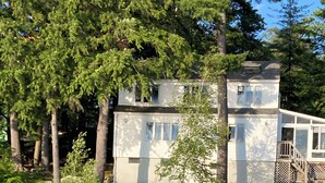 Ein Haus am See mit einem Steg, umgeben von Bäumen.