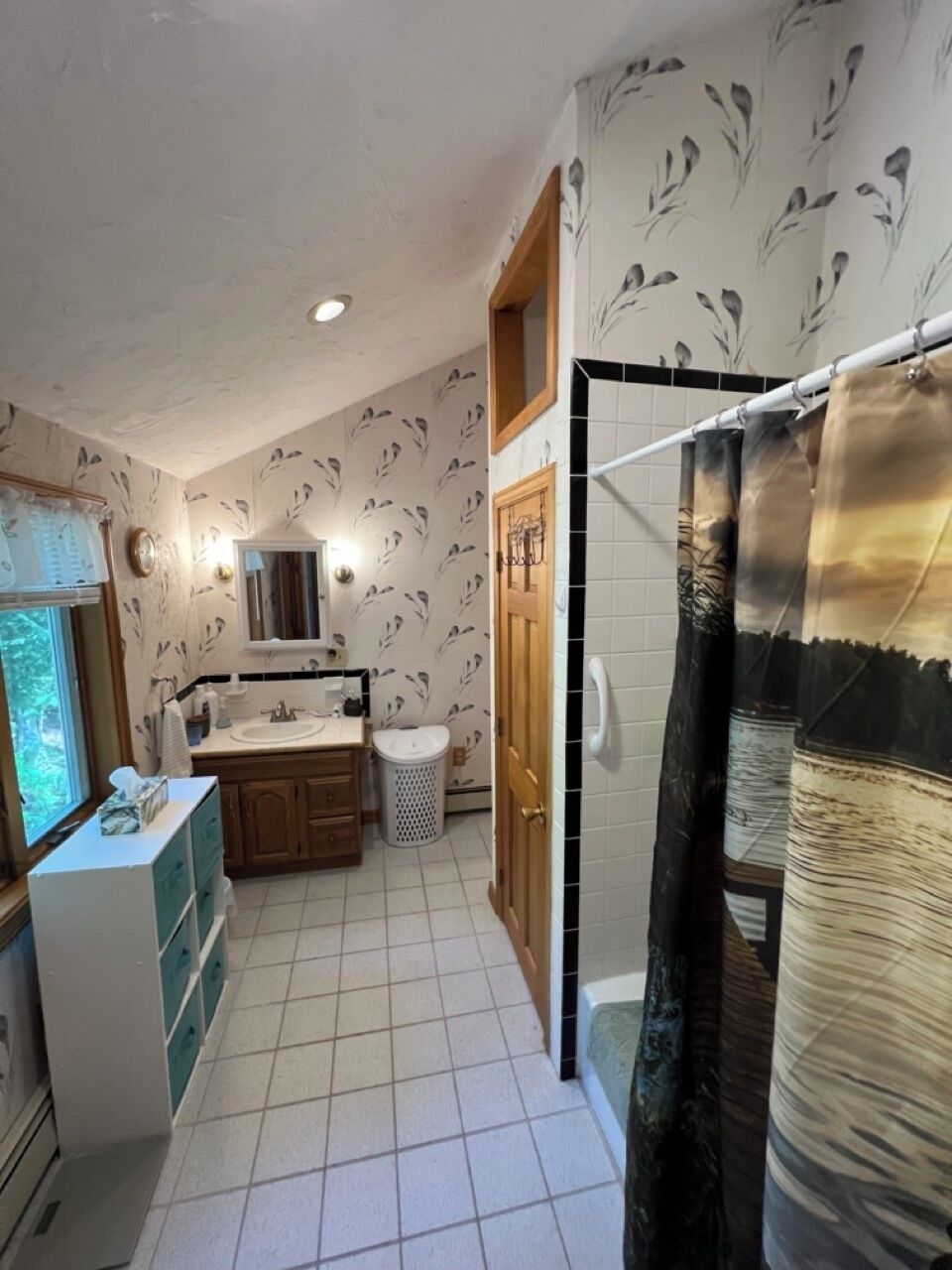 A bathroom with a shower, toilet, sink, and a window.