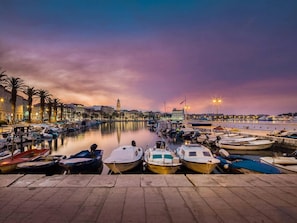 A marina with boats docked, a calm water body, and a cityscape with buildings in the background. - Retreat Inside Diocletian's Palace (Split)