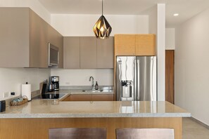 A modern kitchen with a central island, stainless steel appliances, and a pendant light. - 2-bedroom Apt w AC, Gym, Rooftop Infinity Pool Close to Downtown Cabo San Lucas (Cabo San Lucas)