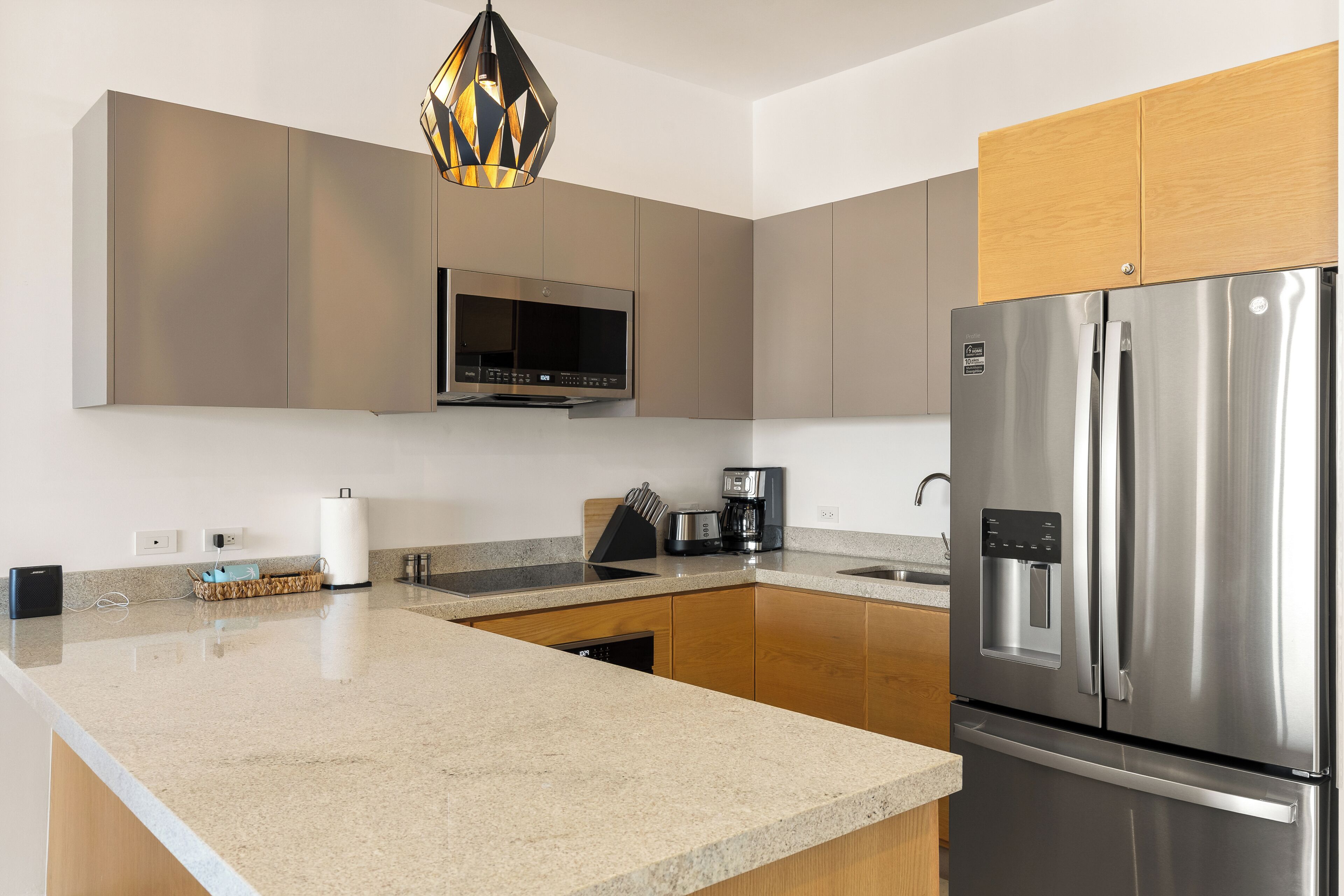 A modern kitchen with a stainless steel refrigerator, a built-in microwave, and a granite countertop.
