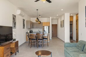 A modern living room with a sofa, a wooden coffee table, and a TV. - 2-bedroom Apt w AC, Gym, Rooftop Infinity Pool Close to Downtown Cabo San Lucas (Cabo San Lucas)