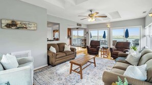 A spacious living room with a ceiling fan, a coffee table, and multiple seating options including sofas and chairs.