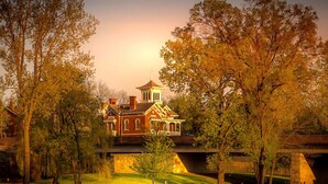 A large, historic building with a prominent tower and multiple chimneys, surrounded by lush trees and a well-maintained lawn. - King Bed w Pull Out Sofa + Murphy Bed (Galena)