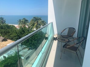 A balcony with a glass railing overlooking a beach and palm trees. - Magnificent apartment on the beach of Santa Marta, ideal for families with children. (Santa marta)