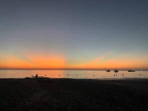 A beach with a sunset, boats, and a person sitting on the sand. - Magnificent apartment on the beach of Santa Marta, ideal for families with children. (Santa marta)
