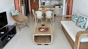 Un salon moderne avec un téléviseur, des meubles en osier, une table à manger avec des chaises et un canapé.