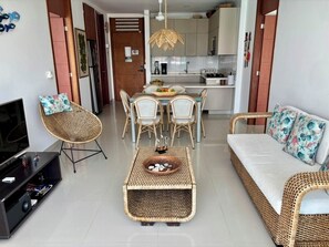 A modern living room with a TV, wicker furniture, a dining table with chairs, and a sofa. - Magnificent apartment on the beach of Santa Marta, ideal for families with children. (Santa marta)