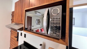 A modern kitchen with a built-in microwave, wooden cabinets, and a black countertop. - Tulum & comfort Travel Apartment 2DB 1BR + Jacuzzi, gym, cinema, swimming pools and more (Tulum)