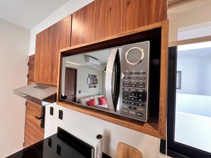 A modern kitchen with a built-in microwave, wooden cabinets, and a black countertop. - Tulum & comfort Travel Apartment 2DB 1BR + Jacuzzi, gym, cinema, swimming pools and more (Tulum)