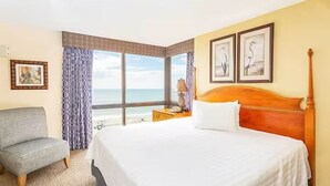 Ein Hotelzimmer mit Bett, Sessel, Nachttisch und Meerblick.
