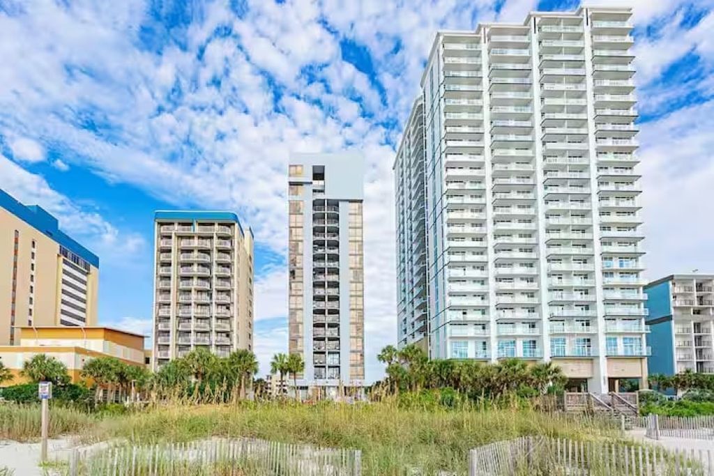 A high-rise building with multiple balconies, a modern architectural style, and a clear sky.