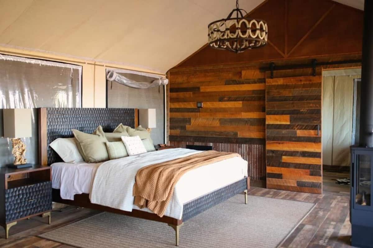 Une chambre à coucher avec un lit, un lambris en bois, un lustre et une table de chevet.