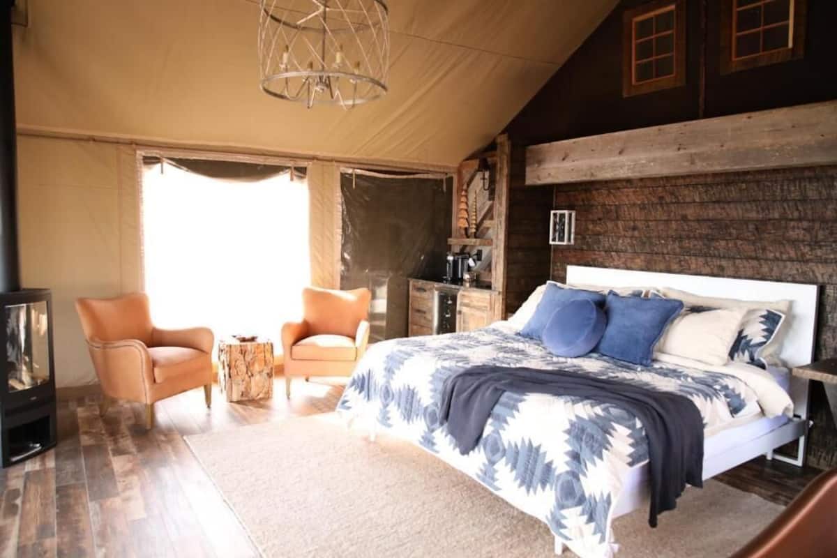 Une chambre à coucher avec un lit, deux chaises, une petite table, un radiateur et un mur en bois.