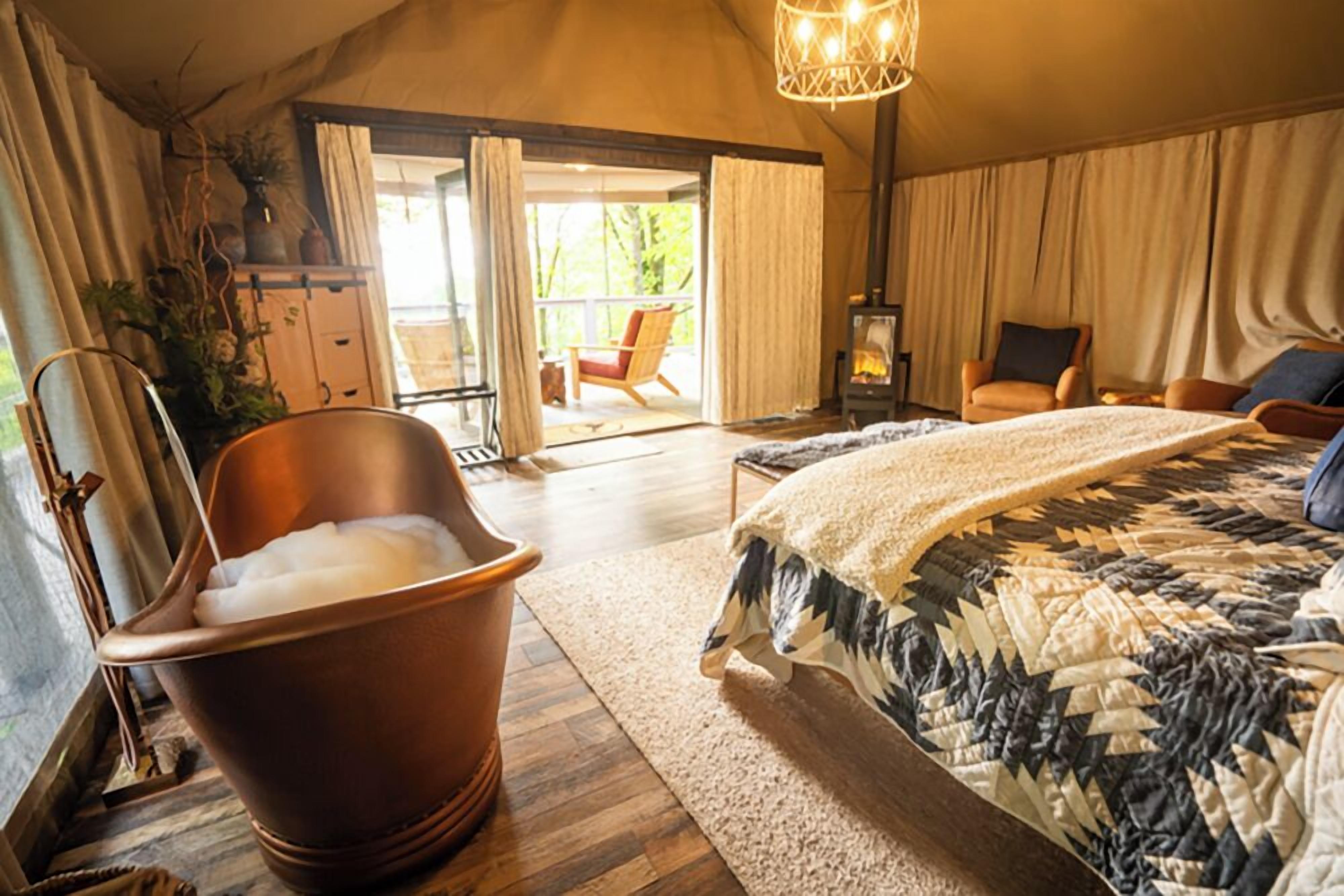 Un dormitorio con una cama grande, una bañera de madera, una silla y una chimenea.