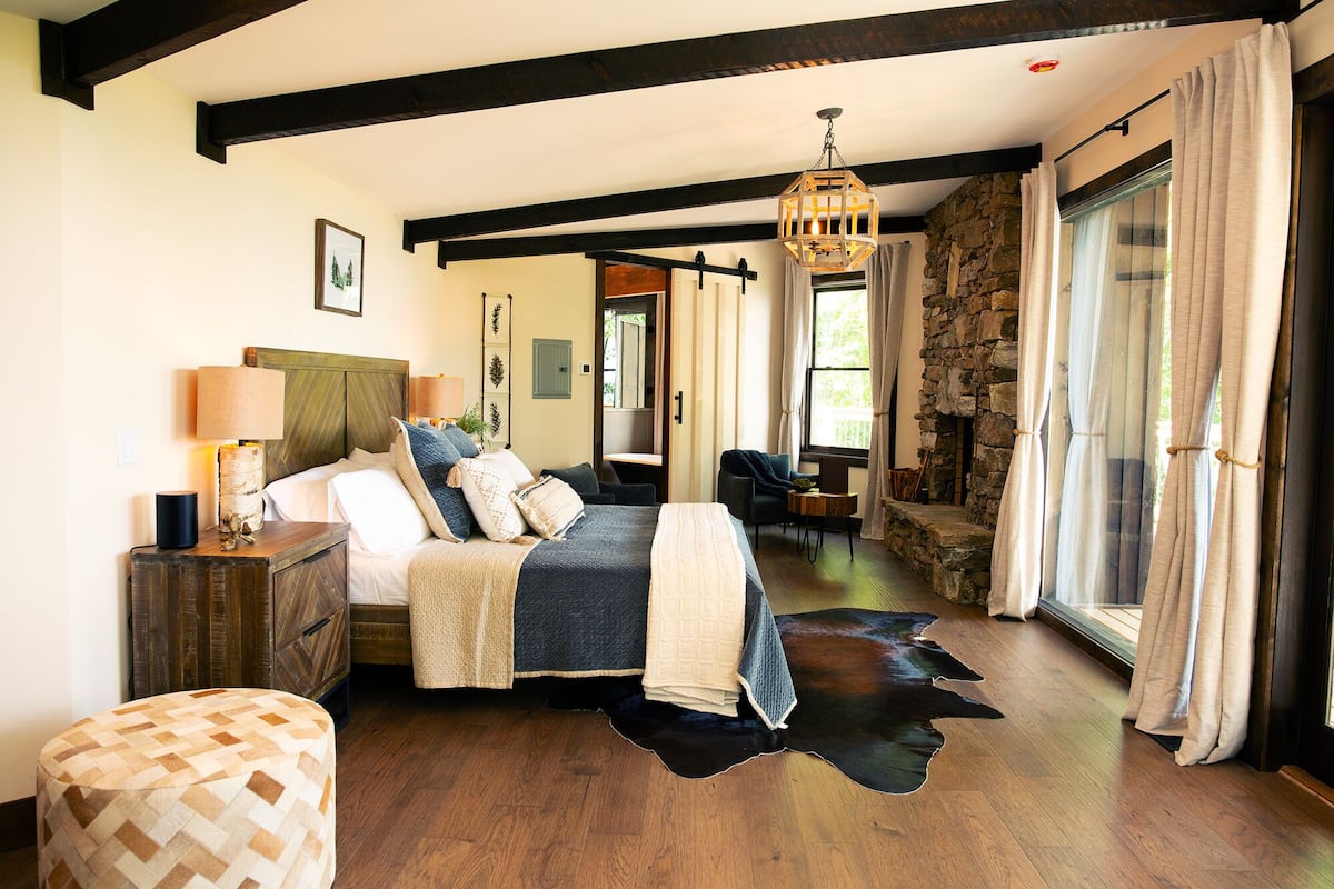 Une chambre à coucher avec un lit, une table de chevet, une lampe et un mur en pierre.