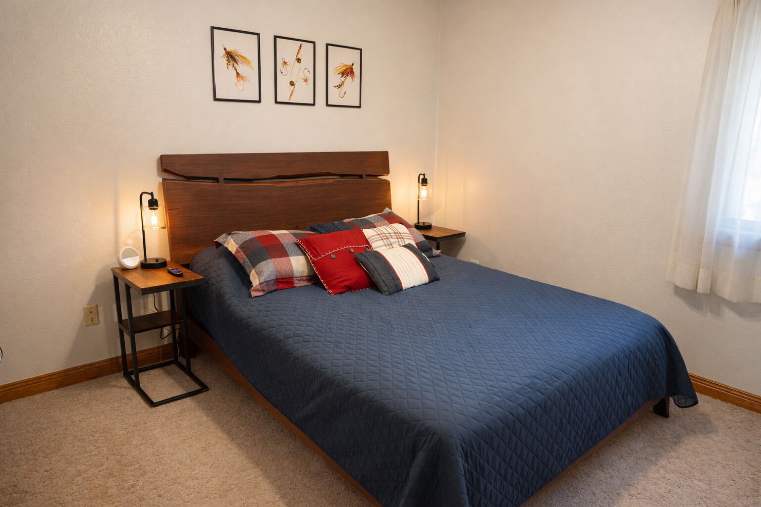 A bedroom with a bed, bedside tables, a headboard, and wall-mounted artwork.